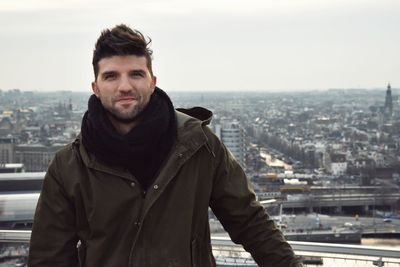 Portrait of man standing in city against sky