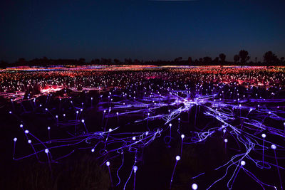 High angle view of illuminated field against clear sky at night