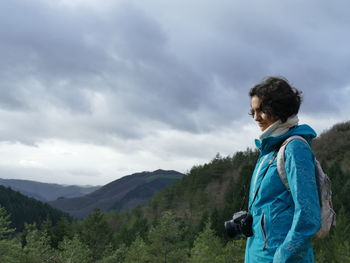 Woman looking away standing on mountain against sky