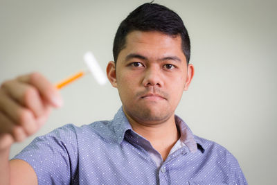 Portrait of man holding razor against white background