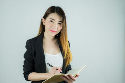 Portrait of beautiful young woman using smart phone against white background