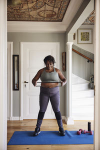 Mature woman exercising with resistance band on exercise mat at home