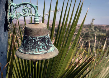 Close-up of tarnished metal bell with fan cactus in the desert 