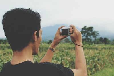 Rear view of man photographing on field