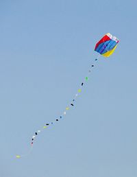 Low angle view of kites flying against clear sky