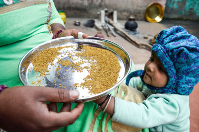 Daughter standing by mother holding food in plate