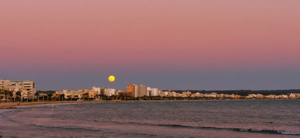 Buildings at waterfront during sunset