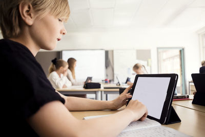 Boy learning through digital tablet in classroom