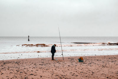 Men fishing at beach against sky