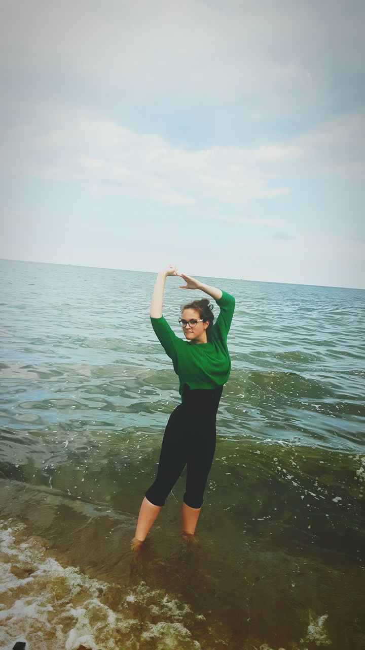 sea, full length, water, lifestyles, leisure activity, horizon over water, beach, person, sky, shore, vacations, casual clothing, smiling, young adult, scenics, tranquil scene, standing, young women, nature, playing, beauty in nature, summer, tranquility, cloud - sky, weekend activities, looking at camera, day