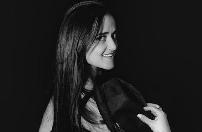 Portrait of young woman with hat against black background