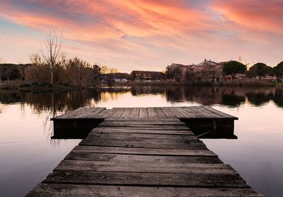 Pier over lake against sky during sunset