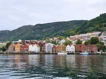 Houses by river and buildings against sky