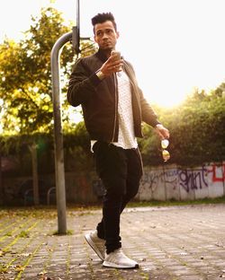 Portrait of young man standing on sidewalk in city