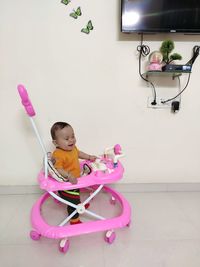 Cute girl sitting on pink floor