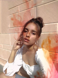 Portrait of young woman sitting against wall