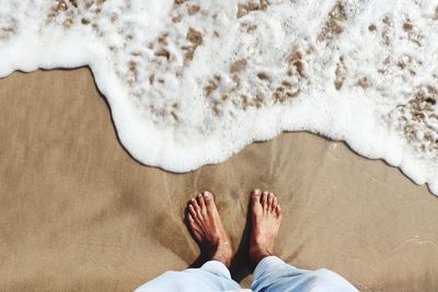 Low section of man relaxing on beach