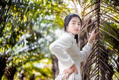 Side view of man looking away while standing against tree