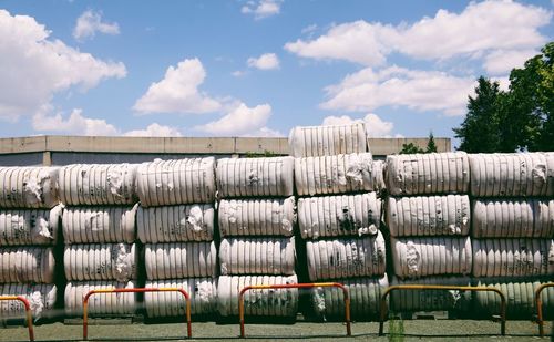 Stacked cotton in fabric containers at factory against sky