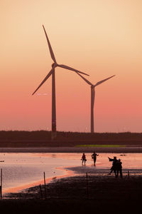 Silhouette people on beach against sky during sunset