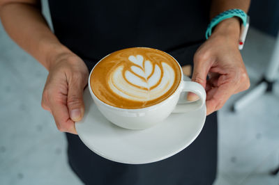 Midsection of man holding cappuccino