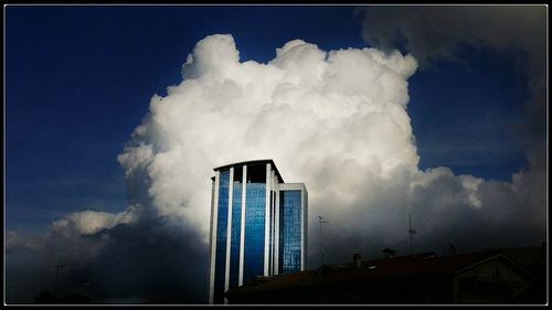 Low angle view of modern building against cloudy sky