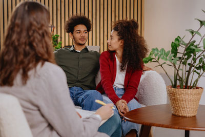 Portrait of smiling friends sitting on bed at home