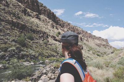 Rear view of woman standing by mountain against sky