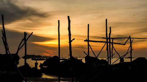 Silhouette sailboats in sea against orange sky