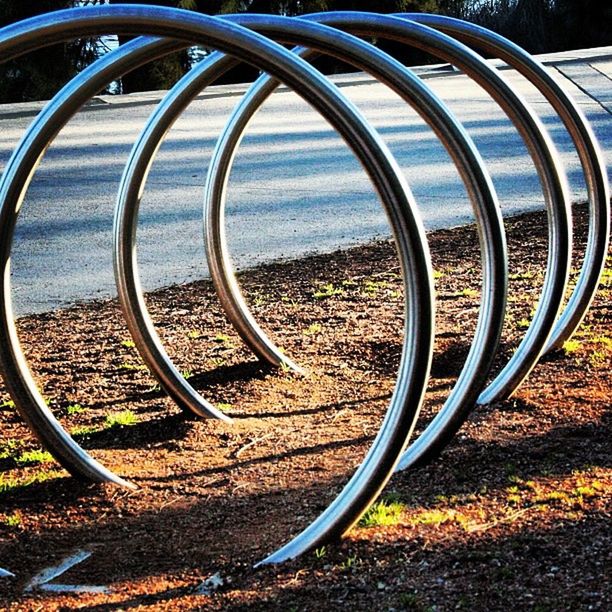metal, field, wheel, railing, circle, sunlight, grass, no people, day, outdoors, nature, close-up, landscape, curve, tire, absence, spiral, geometric shape, tree, steps