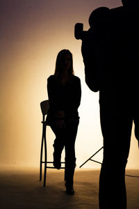 Silhouette man photographing woman in studio