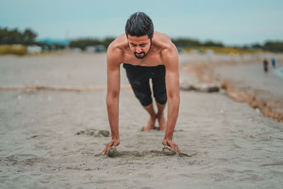 Full length of shirtless man standing on beach