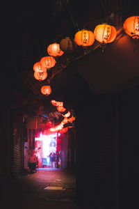 Illuminated lanterns hanging by building at night