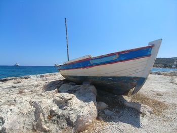 Boat moored on beach against clear blue sky