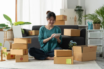 Young woman using digital tablet while sitting on sofa at home