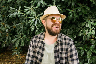 Portrait of young man standing against plants