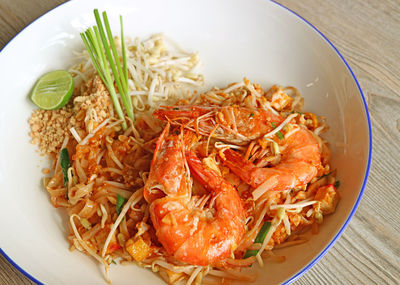 Closeup a plate of pad thai or thai style fried noodle topped with river prawns