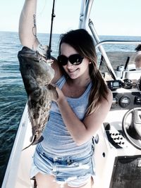 Young woman wearing sunglasses in boat against sea