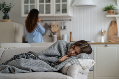 Portrait of young woman lying on bed at home