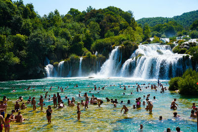 People in river by waterfall