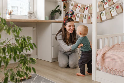 Mother with infant child having fun christmas advent calendar tasks and gifts. baby boy excited