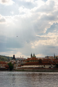 View of buildings at waterfront against cloudy sky