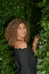 Portrait of smiling woman standing against plants