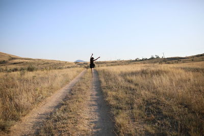 Rear view of man on field against clear sky