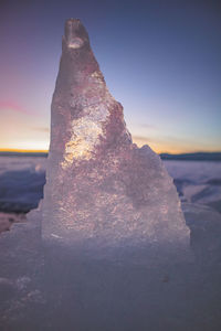 Rock on beach against sky during sunset