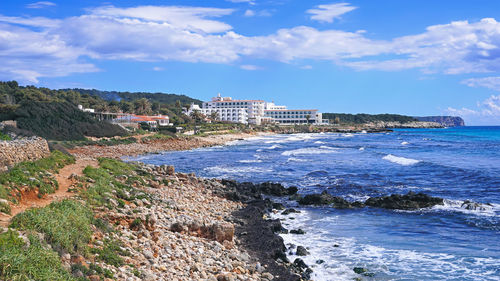 Scenic view of beach by buildings against sky