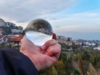 Close-up of hand holding crystal ball against cityscape