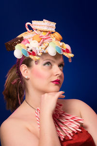 Close-up of thoughtful woman eating waffle against blue background