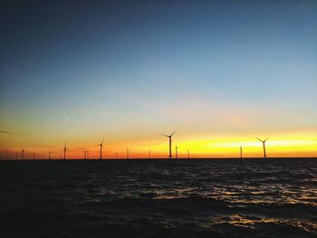 Scenic view of windmills on beach during sunset 