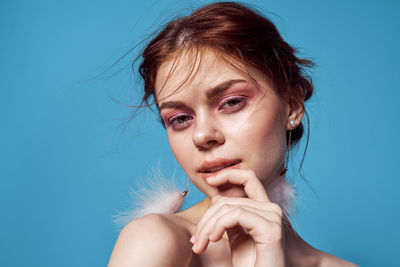 Portrait of young woman against blue background